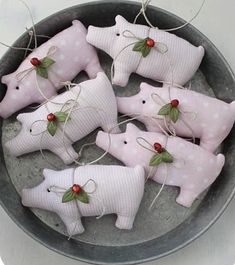 six pink pig ornaments in a bowl with red berries on the nose and green leaves