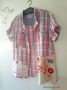 a pink and white shirt hanging on a wall next to a pair of scissors in front of it