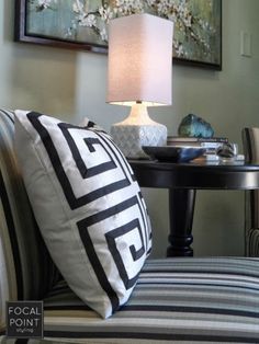 a lamp sitting on top of a table next to a chair with a striped pillow