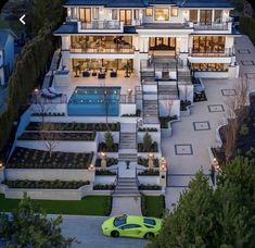 a green car is parked in front of a large house with an outdoor swimming pool