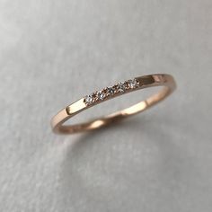 a gold wedding band with three diamonds on the top and bottom, sitting on a white surface