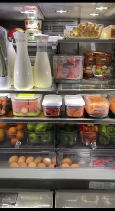 a refrigerator filled with lots of different types of vegetables and fruit in containers next to milk jugs