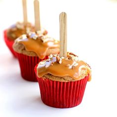 three cupcakes with caramel icing and wooden sticks sticking out of them