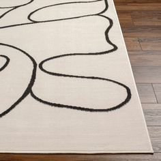 a white rug with black swirls on the top and bottom, sitting on a wooden floor