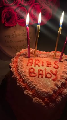 a heart shaped cake with candles in the shape of a baby's name on it