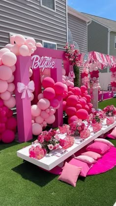 a table set up with pink balloons and flowers