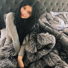 a woman laying on top of a bed covered in fur