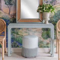 a mirror and stool in front of a wall with a painting on the wall behind it