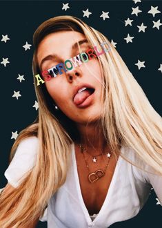 a woman sticking her tongue out in front of the camera with stars all around her