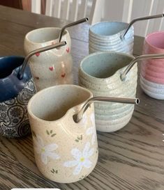 several different colored cups with metal straws in them sitting on a wooden table next to each other