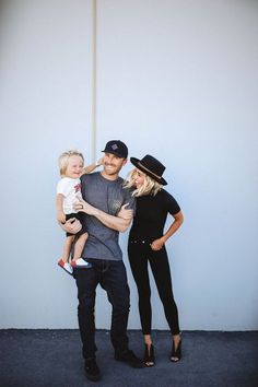 a man, woman and child standing in front of a wall