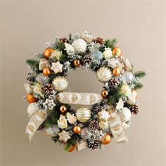 a christmas wreath hanging on the wall with ornaments around it and ribbon tied to it