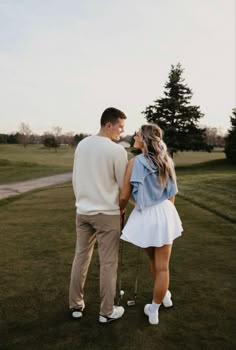 a man and woman standing on top of a lush green field next to each other