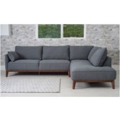 a gray sectional couch sitting on top of a white rug