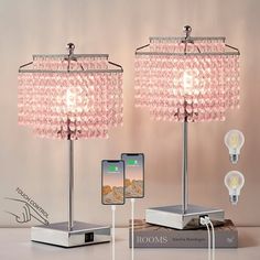 two pink lamps and one cell phone on a table