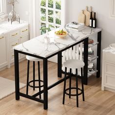 a kitchen table with two stools and a bowl of fruit on the counter top