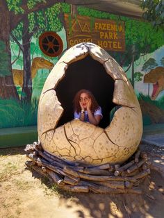 a woman is sitting in a fake egg shell