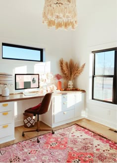 a room with a rug, desk and two windows