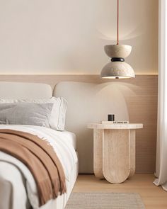 a white bed sitting next to a wooden table on top of a hard wood floor