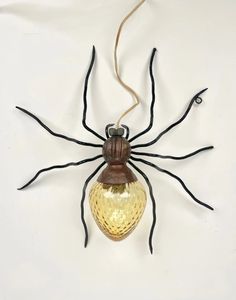 a spider is hanging on the wall with its head turned to look like it's holding a light bulb