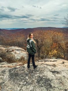 a woman standing on top of a large rock