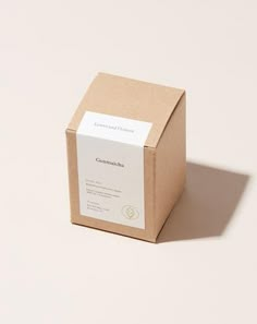 a box with a label on it sitting on a white surface next to a brown paper bag