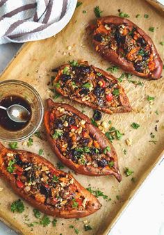 baked stuffed sweet potatoes on a baking sheet with dipping sauce in a glass bottle next to them