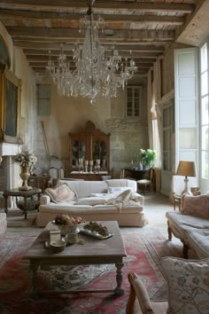 a living room filled with lots of furniture and a chandelier hanging from the ceiling