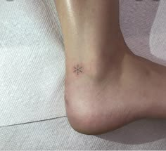 a small snowflake tattoo on the foot of a woman's left ankle