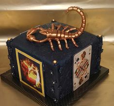 a cake made to look like a box with a scorpion on top and pictures on it