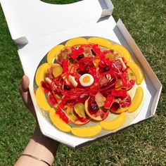 a person holding a yellow plate with fruit on it and an egg in the middle