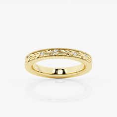 a yellow gold wedding ring with diamonds on the sides and an engraved design in the middle