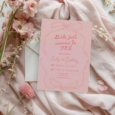 a pink wedding card on top of some flowers