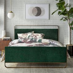 a bedroom with white brick walls and green velvet bedding, potted plant in the corner