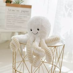 an octopus stuffed animal sitting on top of a wire stand in front of a window