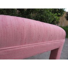 a pink bench sitting on top of a sidewalk