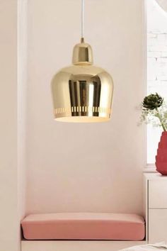 a white and pink room with a gold light fixture hanging from the ceiling above it