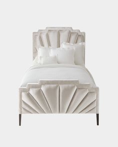 a bed with white linens and pillows on it's headboard, in front of a gray background