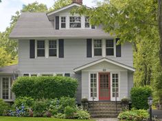 a gray house with black shutters and red door