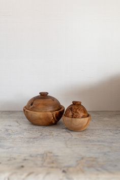 two wooden bowls sitting next to each other on a marble counter top with a white wall in the background