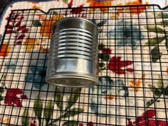 an old tin can sitting on top of a floral tablecloth with a flowered place mat