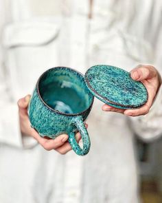 a person holding two tea cups in their hands