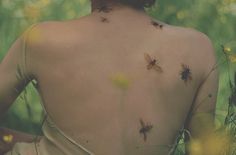 the back of a woman's body with flies on her upper half and chest