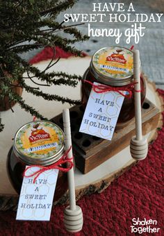 three jars of honey sitting on top of a wooden stand with tags attached to them