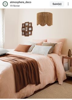 a bed with pink sheets and pillows in a bedroom