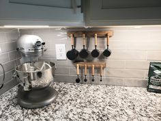 a kitchen counter with pots and pans hanging on the wall next to an electric mixer