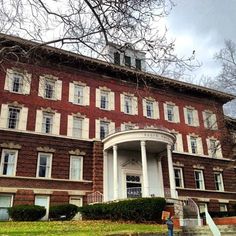 an old red brick building with white trim on the front and stairs leading up to it