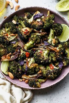 a bowl filled with broccoli, onions and limes on top of a table