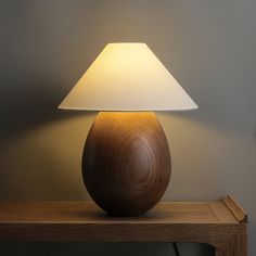 a wooden table lamp with a white shade on it's base sitting on a shelf