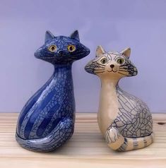 two ceramic cats sitting next to each other